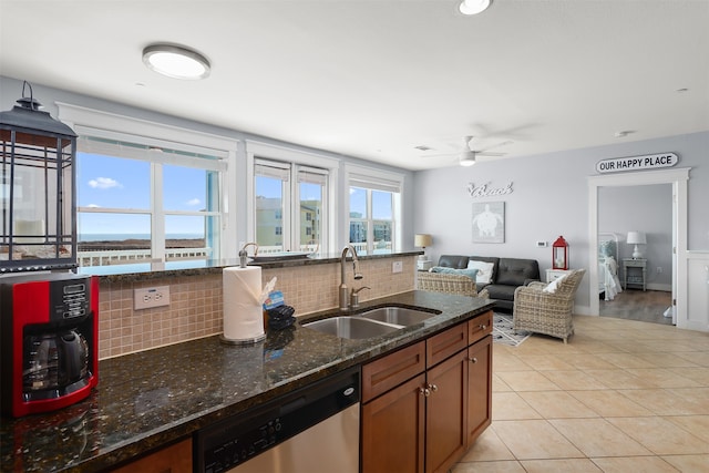 kitchen featuring dark stone counters, ceiling fan, backsplash, dishwasher, and sink