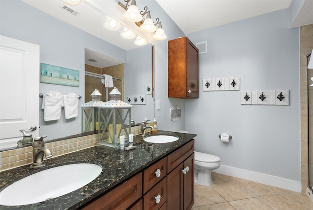 bathroom featuring double sink vanity, tile floors, toilet, and a shower with door