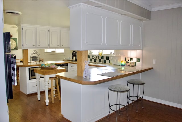 kitchen with white cabinetry, dark wood-type flooring, a kitchen breakfast bar, and kitchen peninsula