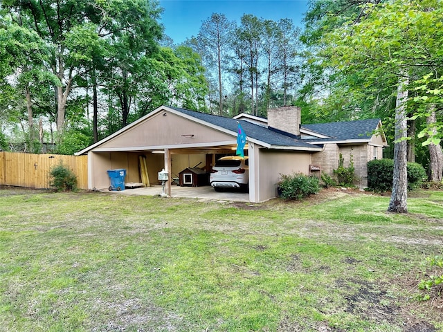 back of house featuring a carport and a yard