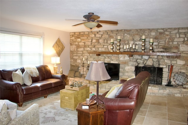 tiled living room with ceiling fan, a fireplace, and a textured ceiling