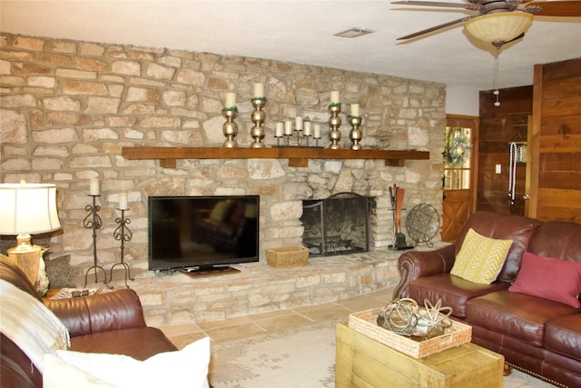 tiled living room featuring ceiling fan and a stone fireplace