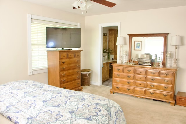 bedroom with ceiling fan, ensuite bathroom, and light carpet