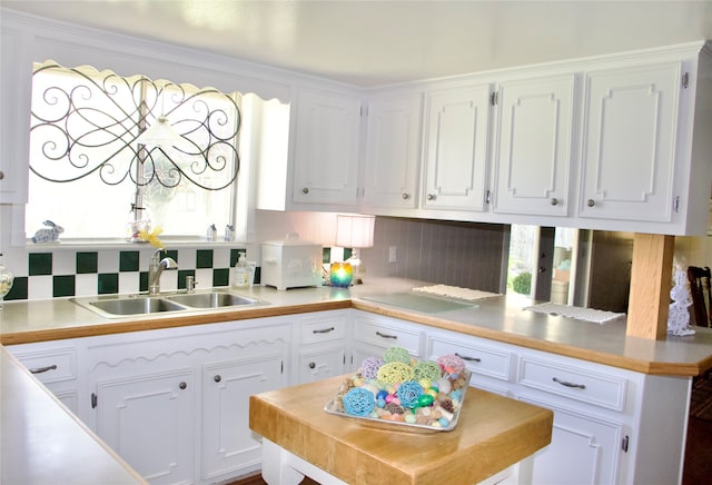 kitchen featuring sink, tasteful backsplash, and white cabinets