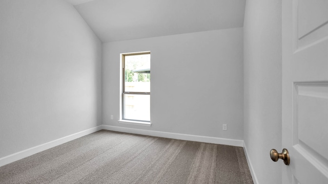 carpeted spare room featuring lofted ceiling