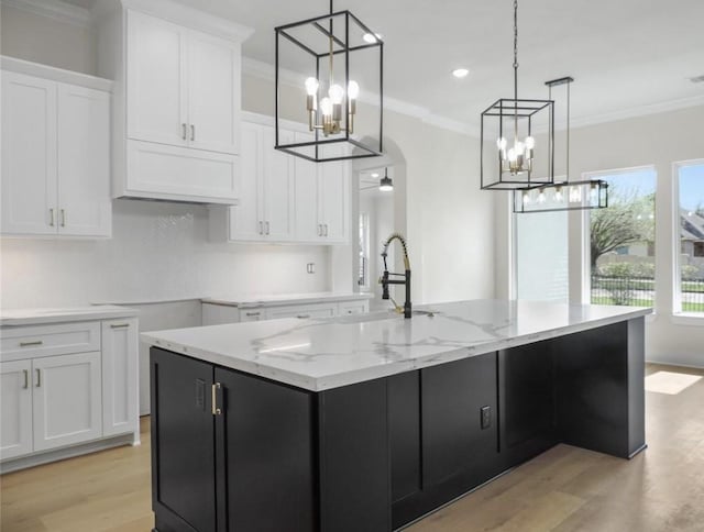 kitchen with light hardwood / wood-style floors, white cabinetry, a kitchen island with sink, and ceiling fan