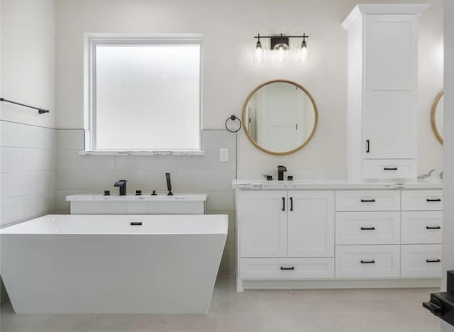 bathroom with a bathing tub, vanity, concrete flooring, and tile walls