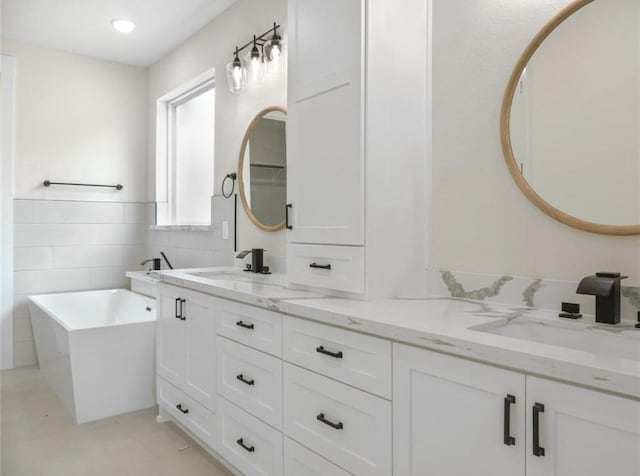 bathroom featuring vanity, a tub to relax in, and tile walls