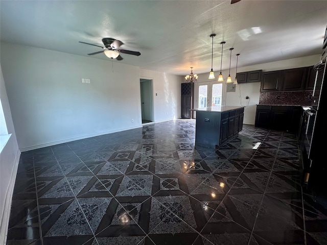 kitchen with a center island, decorative light fixtures, dark tile flooring, and ceiling fan with notable chandelier