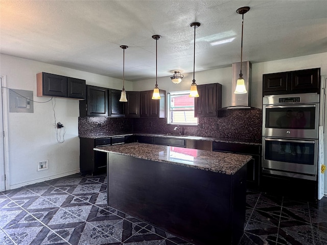 kitchen featuring stainless steel double oven, pendant lighting, tasteful backsplash, and a kitchen island