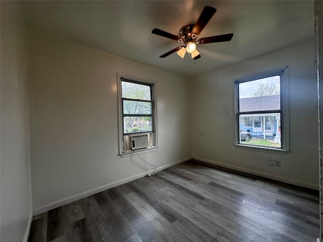 unfurnished room with plenty of natural light, wood finished floors, a ceiling fan, and baseboards