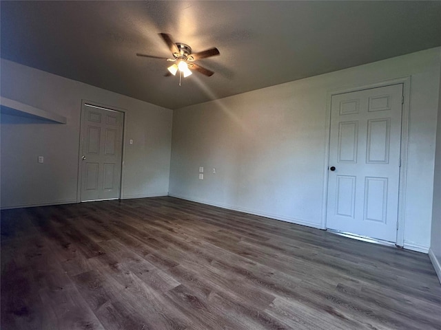 unfurnished bedroom with ceiling fan, baseboards, and dark wood-type flooring