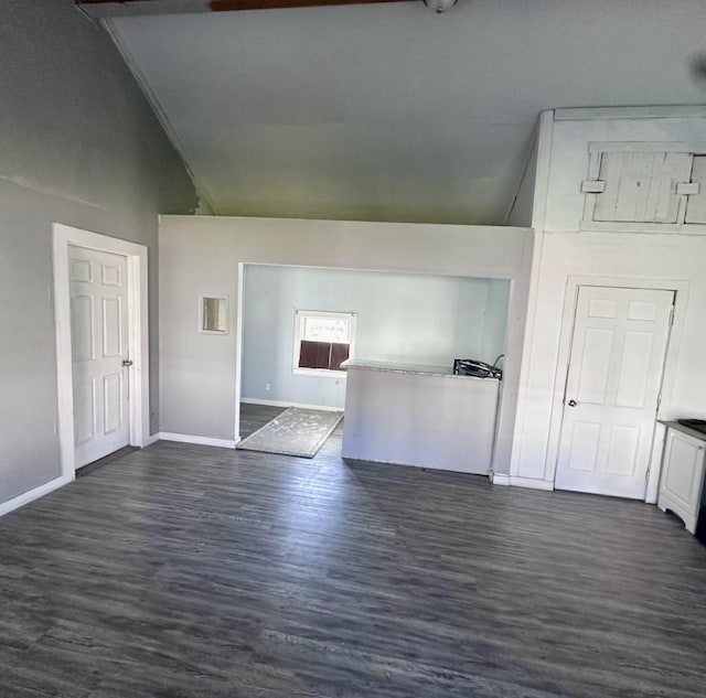 interior space with dark wood-type flooring, high vaulted ceiling, and baseboards