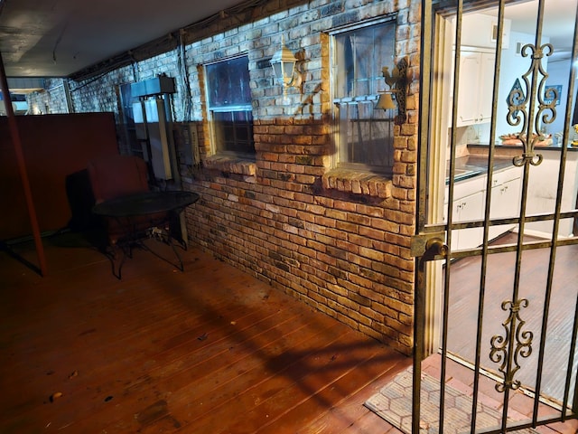 basement featuring brick wall and dark hardwood / wood-style floors