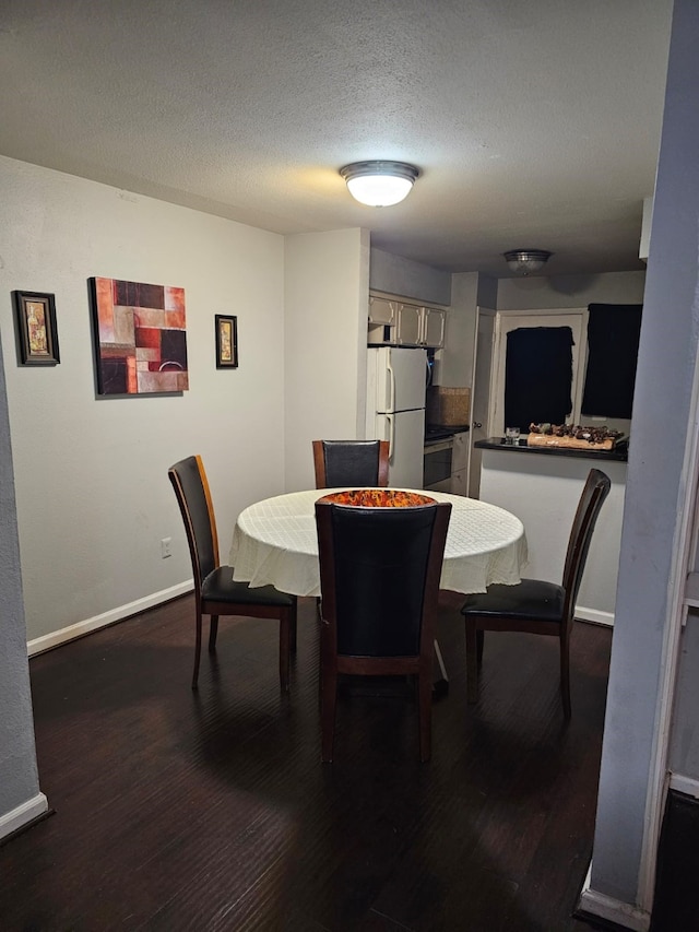 dining area featuring dark wood-type flooring and a textured ceiling