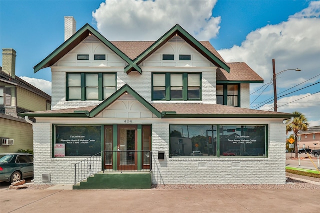 view of front of home with roof with shingles, brick siding, and crawl space