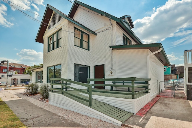 exterior space with a gate, fence, and brick siding