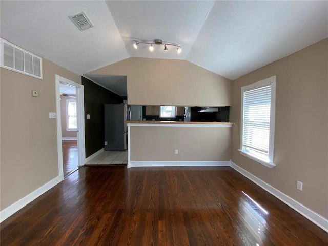 unfurnished living room featuring plenty of natural light, rail lighting, lofted ceiling, and tile flooring