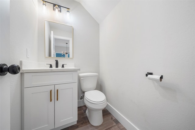 bathroom featuring vanity, lofted ceiling, a notable chandelier, wood-type flooring, and toilet