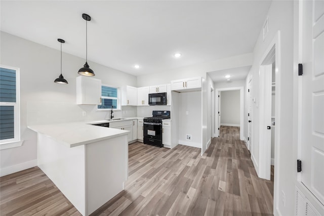 kitchen with kitchen peninsula, white cabinetry, light hardwood / wood-style floors, and black appliances