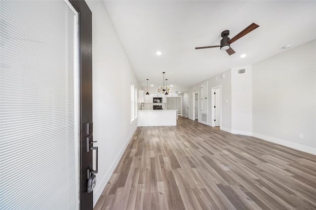 unfurnished living room with wood-type flooring and ceiling fan with notable chandelier