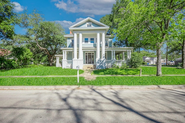 greek revival inspired property featuring a front yard and covered porch