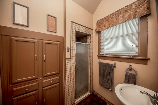 bathroom with lofted ceiling, a shower with door, and sink