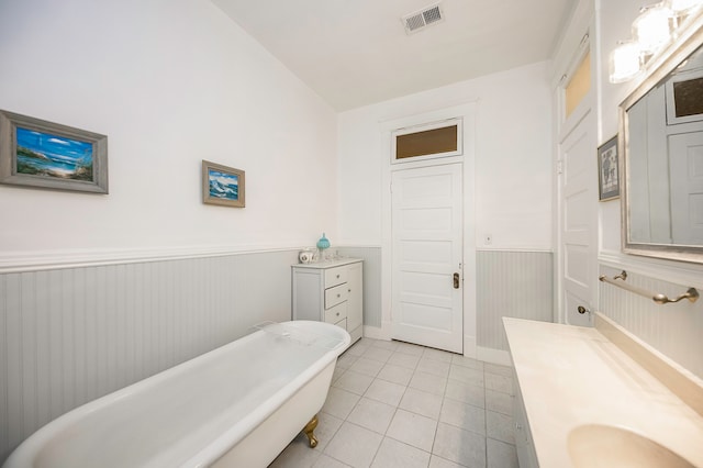 bathroom featuring vanity, a tub to relax in, vaulted ceiling, and tile patterned floors