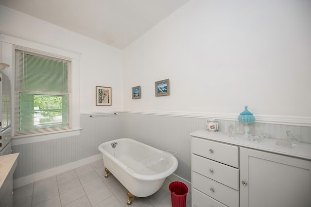 bathroom with a bath, lofted ceiling, vanity, and tile patterned floors