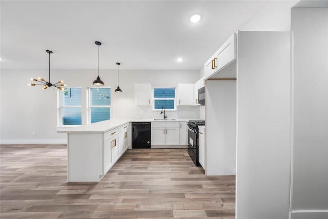 kitchen featuring an inviting chandelier, kitchen peninsula, light hardwood / wood-style flooring, black appliances, and pendant lighting