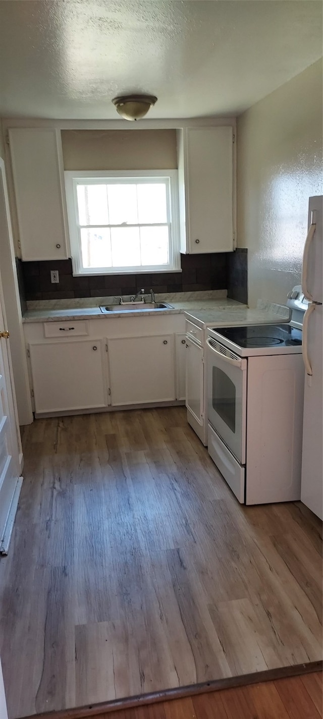 kitchen featuring sink, white appliances, white cabinetry, and light hardwood / wood-style flooring