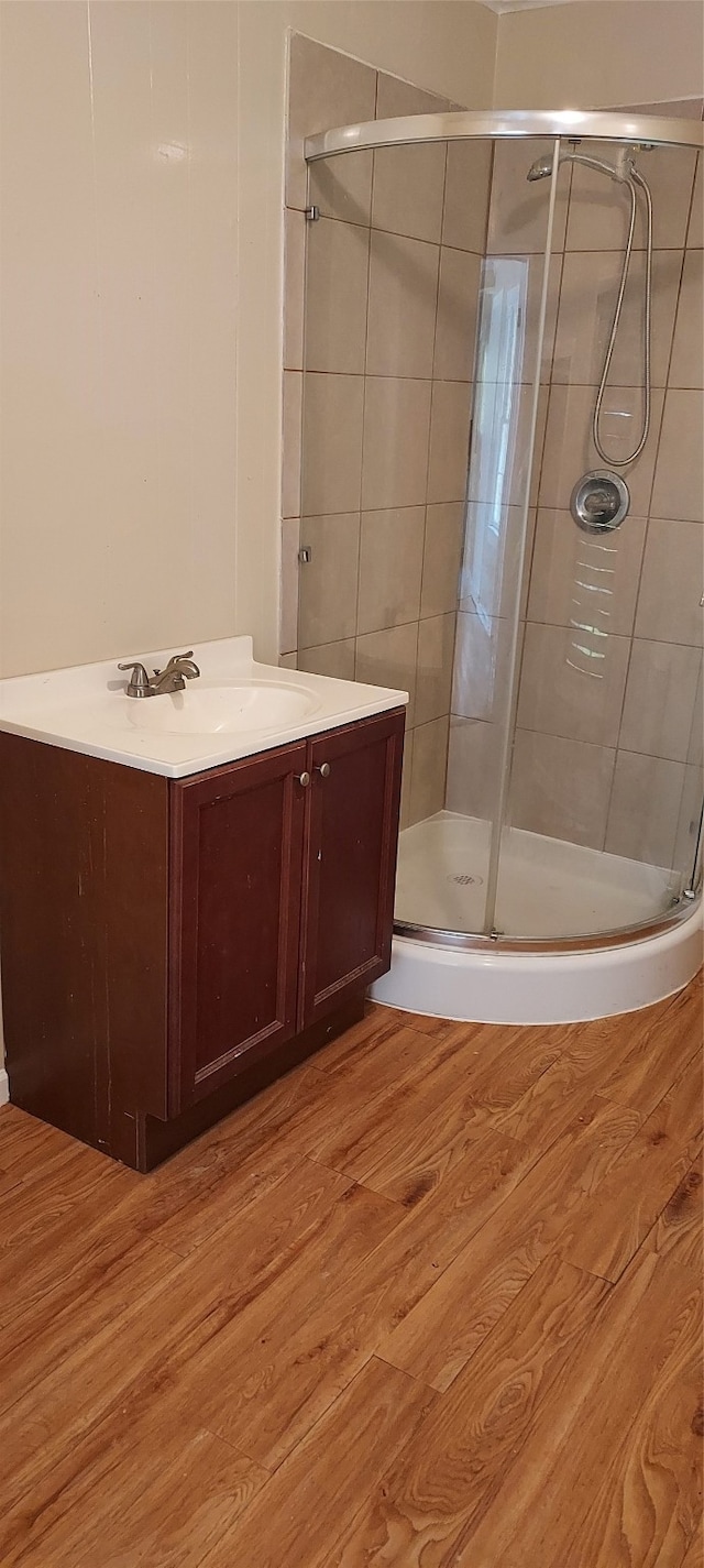 bathroom with wood-type flooring, a shower with shower door, and vanity