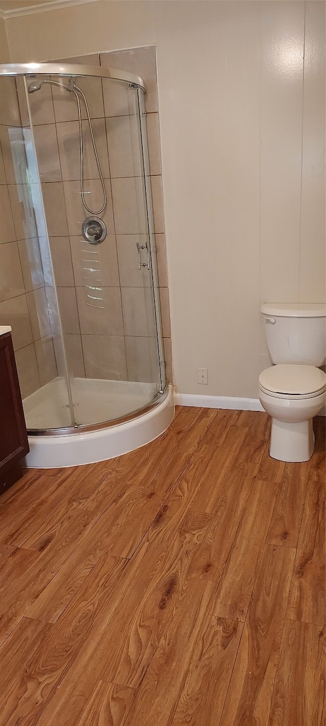 bathroom featuring a shower with door, toilet, vanity, and hardwood / wood-style floors