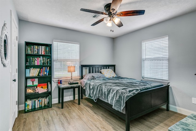 bedroom featuring ceiling fan, a textured ceiling, and light wood-type flooring