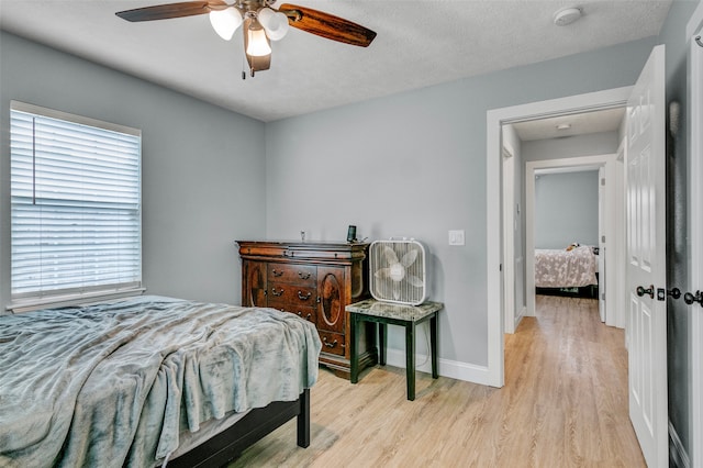 bedroom with ceiling fan, a textured ceiling, light wood-type flooring, and multiple windows