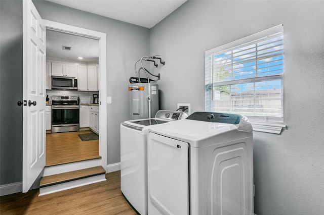 washroom with washer hookup, washing machine and dryer, water heater, and light wood-type flooring