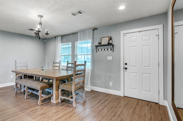 dining space with an inviting chandelier, light hardwood / wood-style flooring, and a textured ceiling