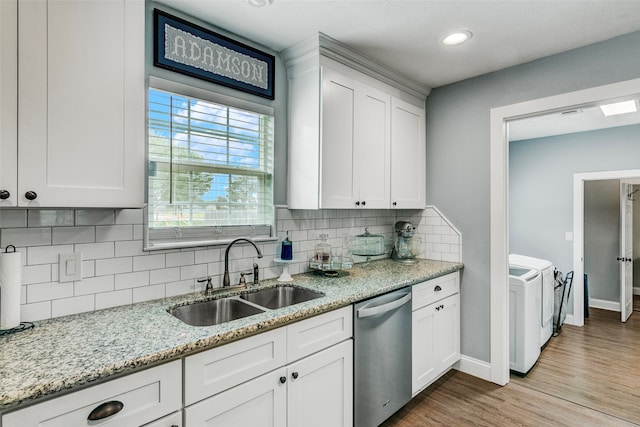 kitchen with stainless steel dishwasher, tasteful backsplash, light hardwood / wood-style flooring, washer and clothes dryer, and sink