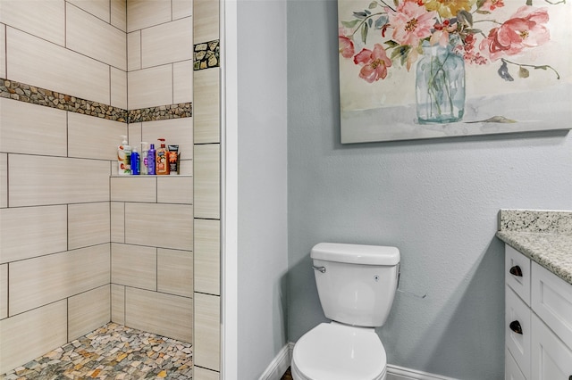 bathroom with vanity, toilet, and tiled shower