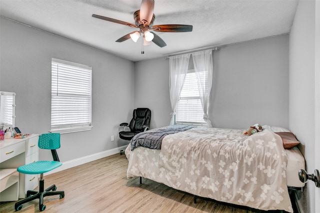 bedroom with multiple windows, a textured ceiling, light hardwood / wood-style flooring, and ceiling fan