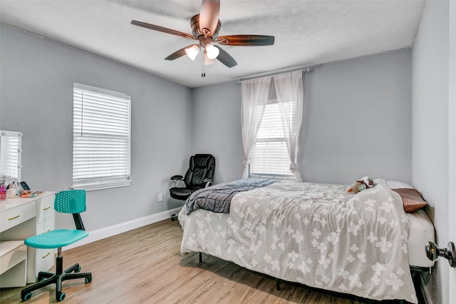 bedroom with multiple windows, a textured ceiling, light hardwood / wood-style floors, and ceiling fan