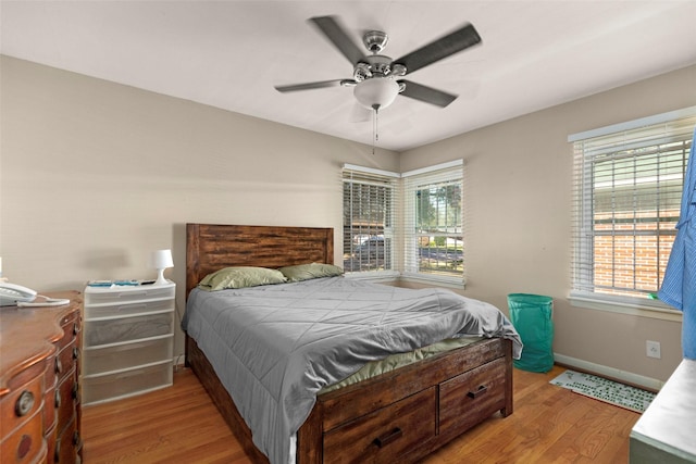 bedroom featuring a ceiling fan, baseboards, and wood finished floors
