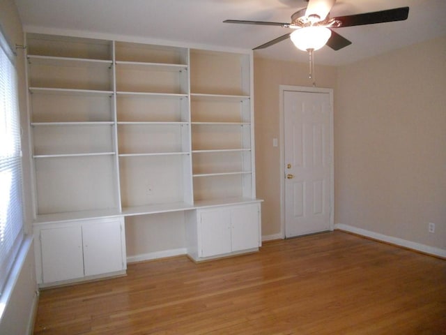 interior space featuring light wood-type flooring, baseboards, a ceiling fan, and built in study area