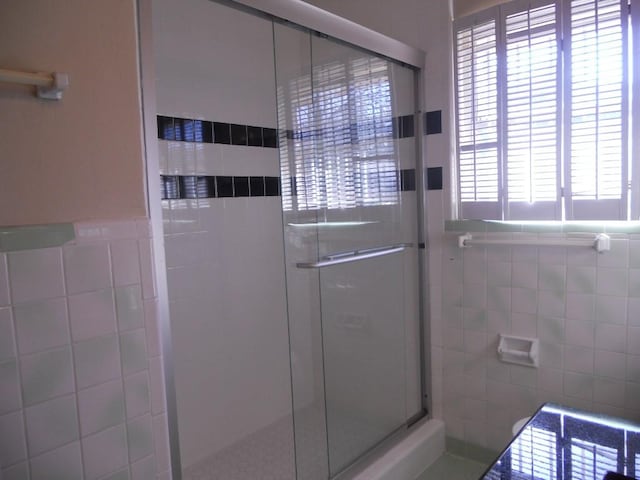 full bath featuring tiled shower and tile walls
