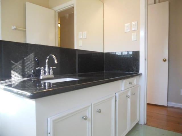 kitchen with dark countertops, tasteful backsplash, white cabinets, and a sink