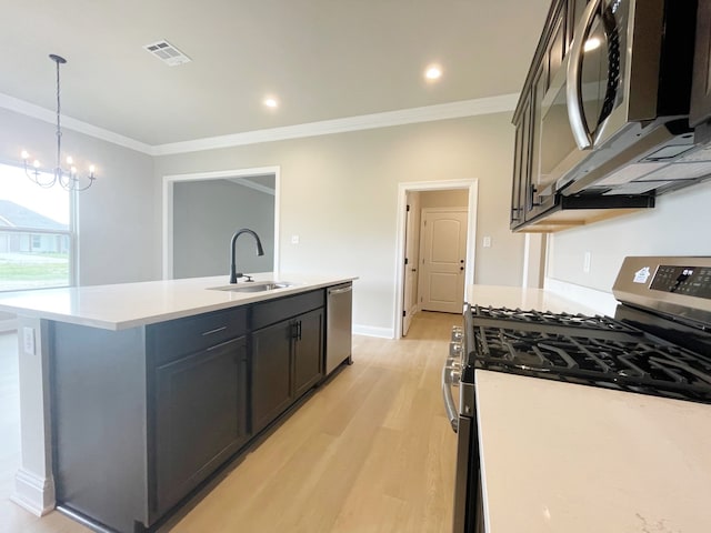 kitchen featuring appliances with stainless steel finishes, a kitchen island with sink, hanging light fixtures, light wood-type flooring, and sink