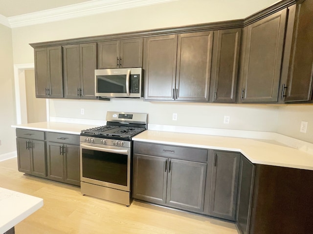 kitchen featuring appliances with stainless steel finishes, light wood-type flooring, ornamental molding, and dark brown cabinetry