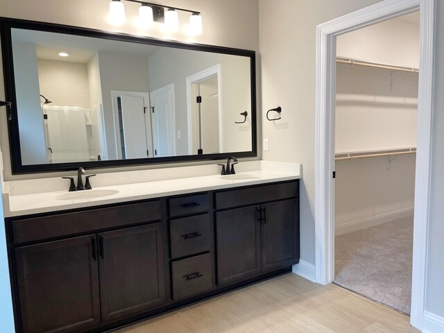 bathroom with double vanity, hardwood / wood-style floors, and a shower