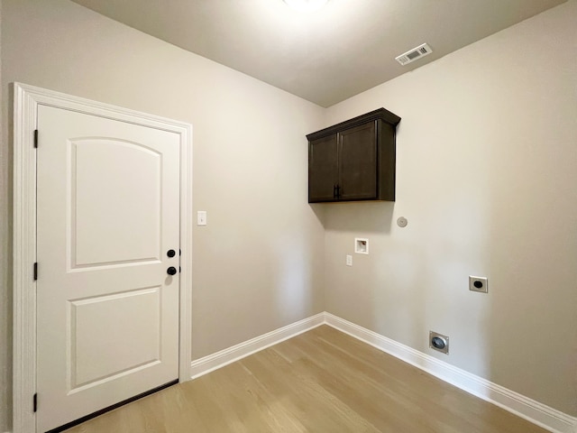 clothes washing area with cabinets, light wood-type flooring, hookup for an electric dryer, and washer hookup