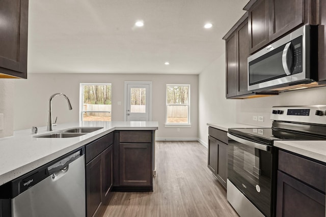 kitchen featuring stainless steel appliances, plenty of natural light, sink, and light hardwood / wood-style flooring